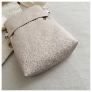 Detail of off-white lychee grain leather texture with gold metal zipper and hardware