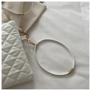 Détail du sac à main matelassé blanc avec ferrures dorées et poignée circulaire élégante