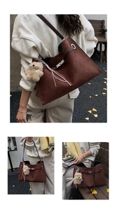Detail of vintage brown suede tote bag with metal turn-lock and teddy bear charm accessory