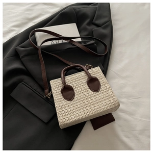 Detailed straw handbag with brown leather handles on a minimalist fashion background