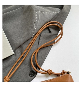 Detail of brown lychee grain leather bag with knotted strap and gold metal zipper