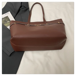 Close-up of brown leather tote bag with elegant gold buckle and textured leather detail