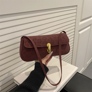 Sac baguette rouge foncé avec relief léopard et fermoir doré porté par un mannequin
