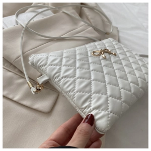 Vue détaillée du sac matelassé blanc avec boucle en forme de nœud doré et bandoulière