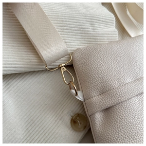 Close-up of beige lychee grain leather bag with gold hardware and canvas strap