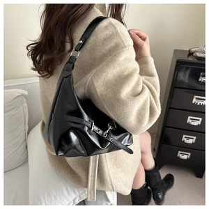 Détail du sac hobo noir brillant avec lanières à œillets argentés et accents métalliques