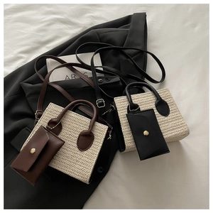 Close-up of woven straw tote bags with leather trim and gold metal hardware detail