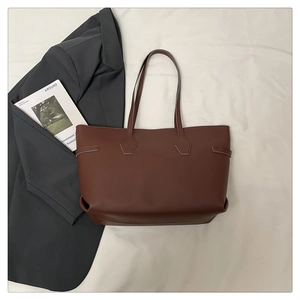 Flat lay of a brown leather tote bag paired with a gray blazer and fashion magazine