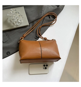 Brown rectangular shoulder bag with fine straps shown next to a smartphone for size reference