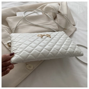 Détail d'un sac bandoulière blanc matelassé avec un nœud doré et une texture douce en similicuir
