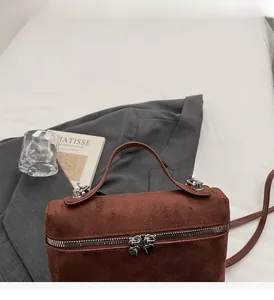 Detailed shot of brown matte box-shaped handbag with unique silver heart zippers