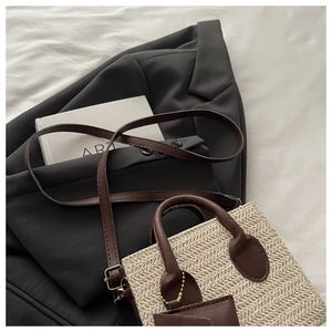 Detail of cream straw handbag showing herringbone texture and brown leather straps