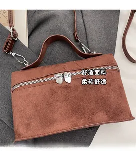 Detailed view of brown suede handbag with decorative silver heart-shaped zipper pulls