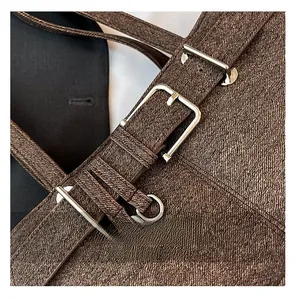 Close-up of textured coffee brown fabric bag with silver metal buckles and adjustable strap