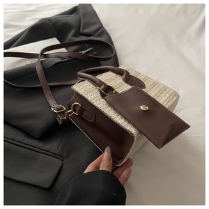 Detail of minimalist straw tote bag with brown leather trim and detachable pouch accessory