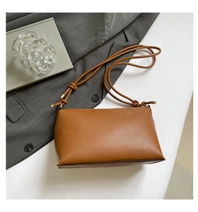 Detail of brown litchi pattern leather bag showing knotted strap and metal clasp