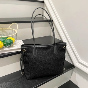 Grand sac cabas noir en laine d'agneau avec poignées en cuir sur un escalier