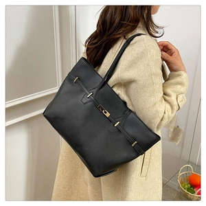 Detail of minimalist black matte tote bag with gold hardware and slim shoulder strap