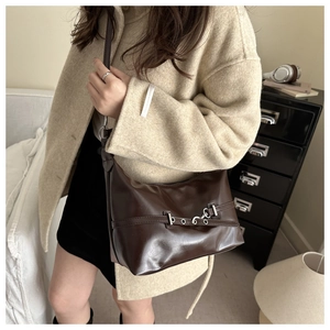 Close-up of a dark brown shoulder bag with silver hardware on a wool coat outfit