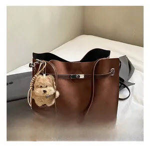 Detail of brown suede tote bag featuring a decorative belt strap and metal buckle closure