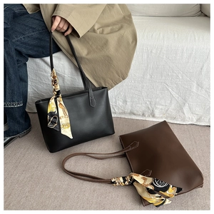 Close-up of retro tote bag with smooth leather finish and decorative silk scarf handle