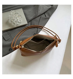 Interior detail of a brown leather shoulder bag with zipper and cream fabric lining