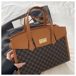 Close-up of brown patchwork handbag with retro monogram pattern and golden twist lock