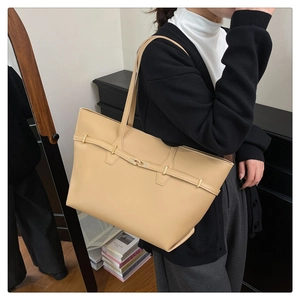 Detail showing high-capacity beige leather tote bag with elegant gold buckle and slim straps