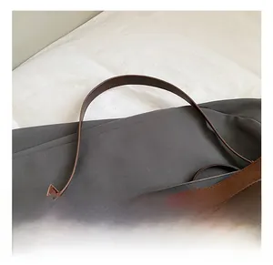 Detailed macro view of dark brown suede bag featuring leather handle and metal twist lock