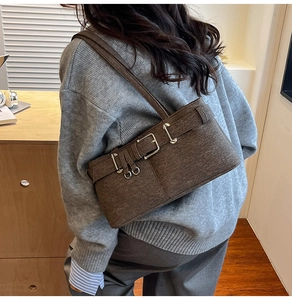 Close-up of brown tweed shoulder bag with vintage metal buckle on a model's arm