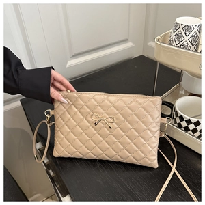 Détail du sac à main matelassé beige avec fermoir en forme de nœud doré et texture fine