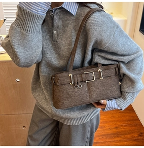 Detail of dark brown tweed shoulder bag with silver buckle worn with a winter sweater