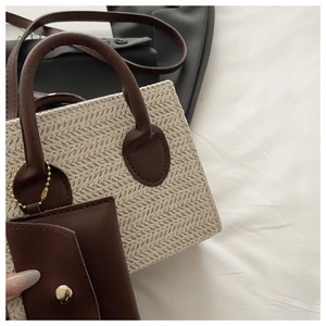 Close-up of woven straw tote bag with brown leather handles and mini hanging coin purse