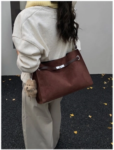 Detail of dark brown matte suede tote bag with metal buckle and cute bear pendant
