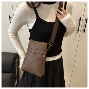 Detail of dark brown lychee texture leather phone bag with adjustable wide fabric strap