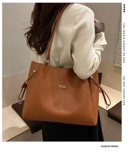 Detail of minimalist brown tote bag with side drawstring and metal ring on model