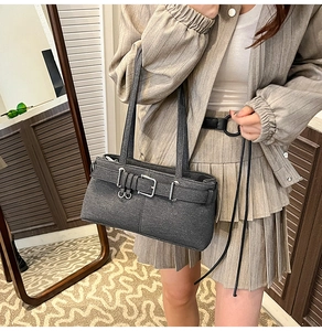 Detail of dark grey felt shoulder bag with buckle strap on a striped blazer