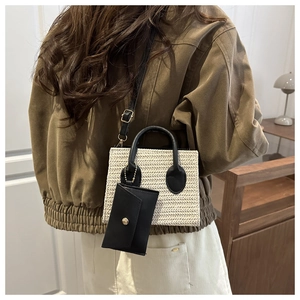 Detail of woven straw handbag with black leather straps and hanging coin purse