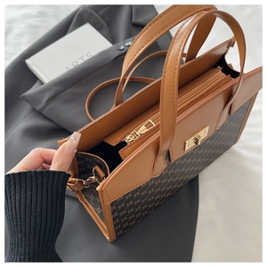 Detail view of large brown tote bag with vintage monogram and gold hardware accents