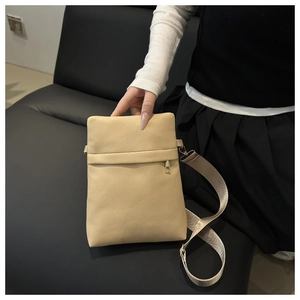 Detailed view of beige pebble grain leather phone bag with gold zipper and wide strap
