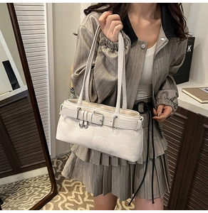 Detail of off-white shoulder bag featuring lychee texture and silver buckle strap