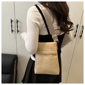 Detailed back view of a beige crossbody bag with lychee texture and fabric strap