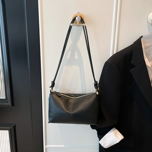 Minimalist black lychee texture shoulder bag with knotted strap detail and metal zipper