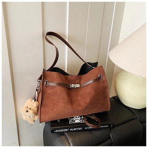 Detailed view of deep brown suede tote with silver twist lock and plush bear charm decor