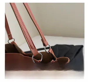 Detail view of silver metal ring buckle and stitching on brown leather tote bag