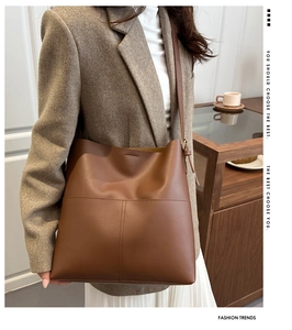 Detail of caramel leather bucket bag with vertical stitching and metal adjustment buckle