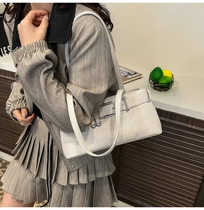 Close-up of off-white textured leather baguette bag with silver metal buckles on a model