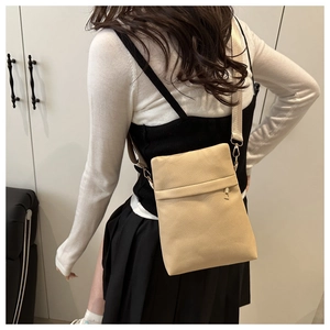 Detail of light beige pebbled leather crossbody bag with wide strap and gold hardware