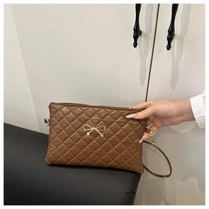 Détail de la texture matelassée en cuir PU marron avec un nœud doré sur le sac
