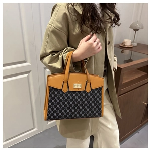 Detail of vintage tote bag with chain pattern, golden lock, and ginger leather accents